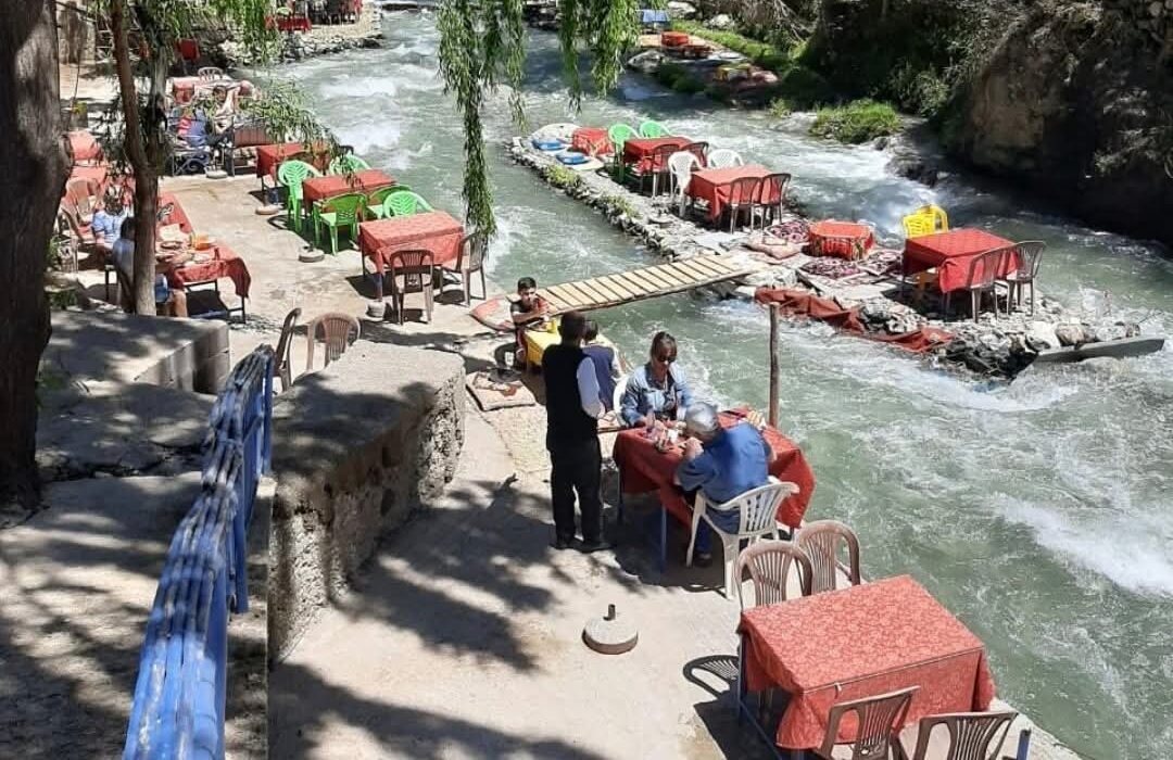 Aerial view of red lounges over Ourika river with visitors walking