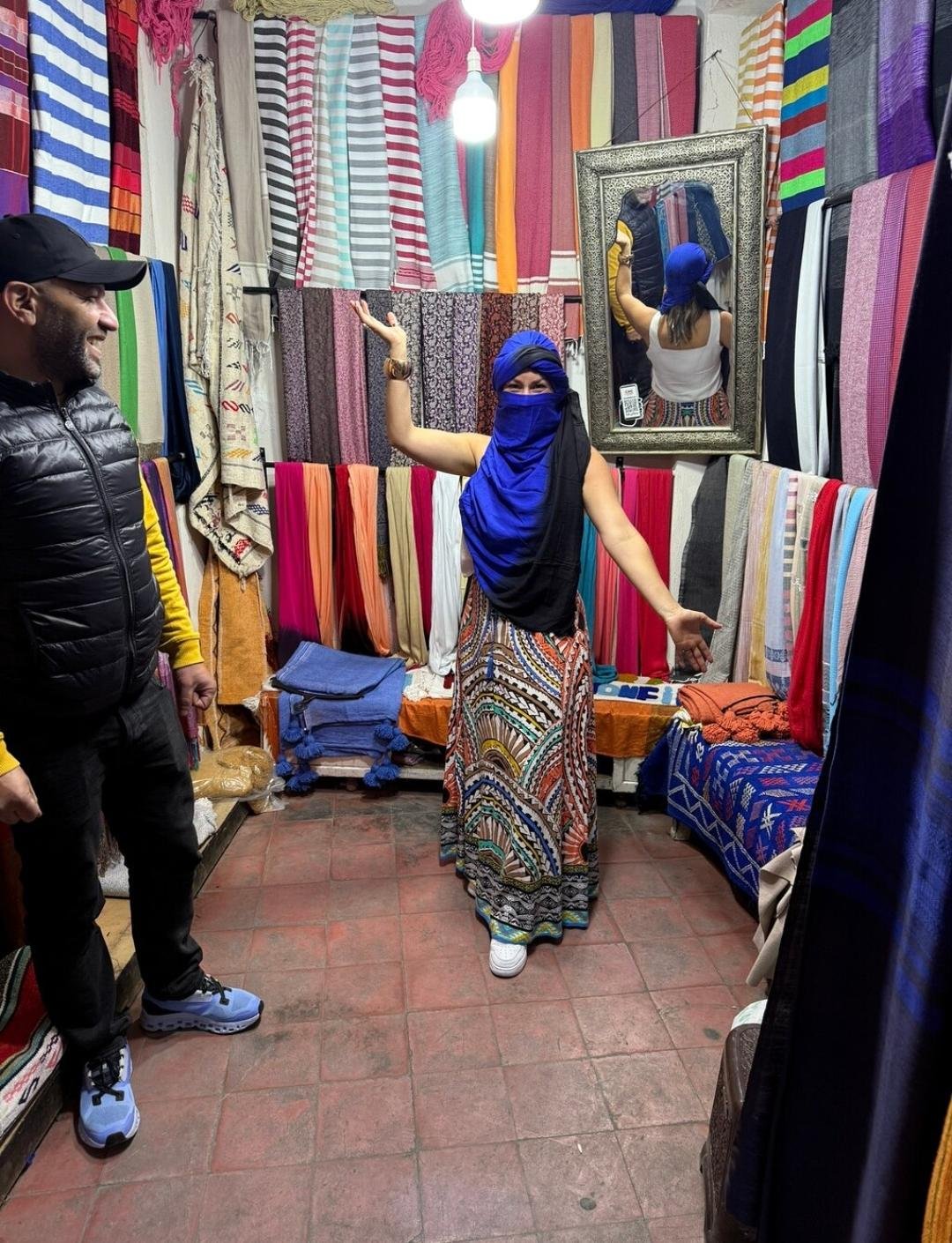 Woman shopping for a traditional Moroccan scarf in Marrakech souk