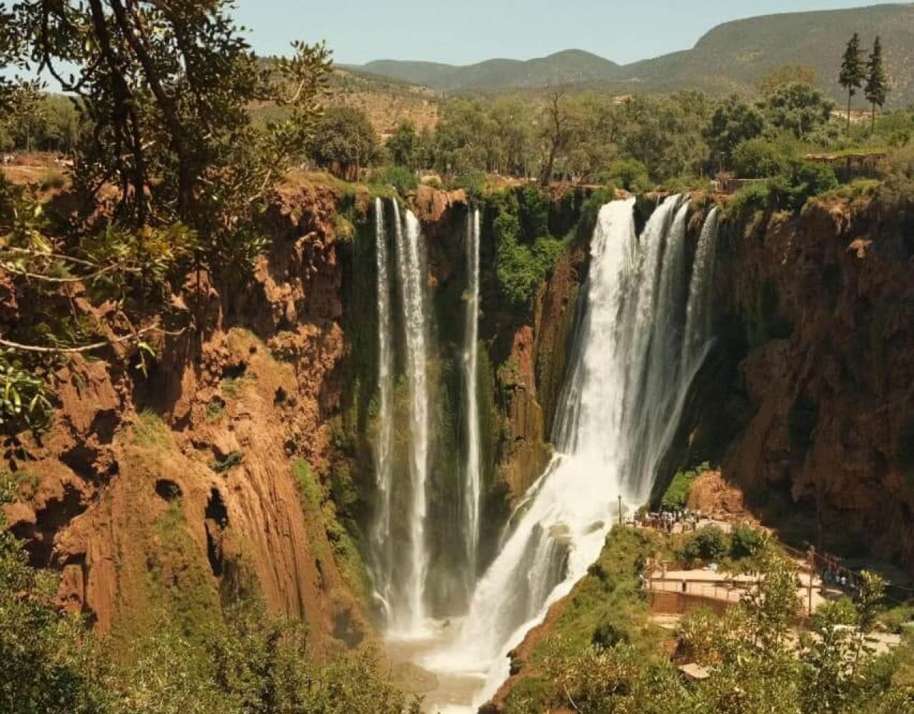 Ouzoud Falls viewed from a platform with a person standing atop the cliff