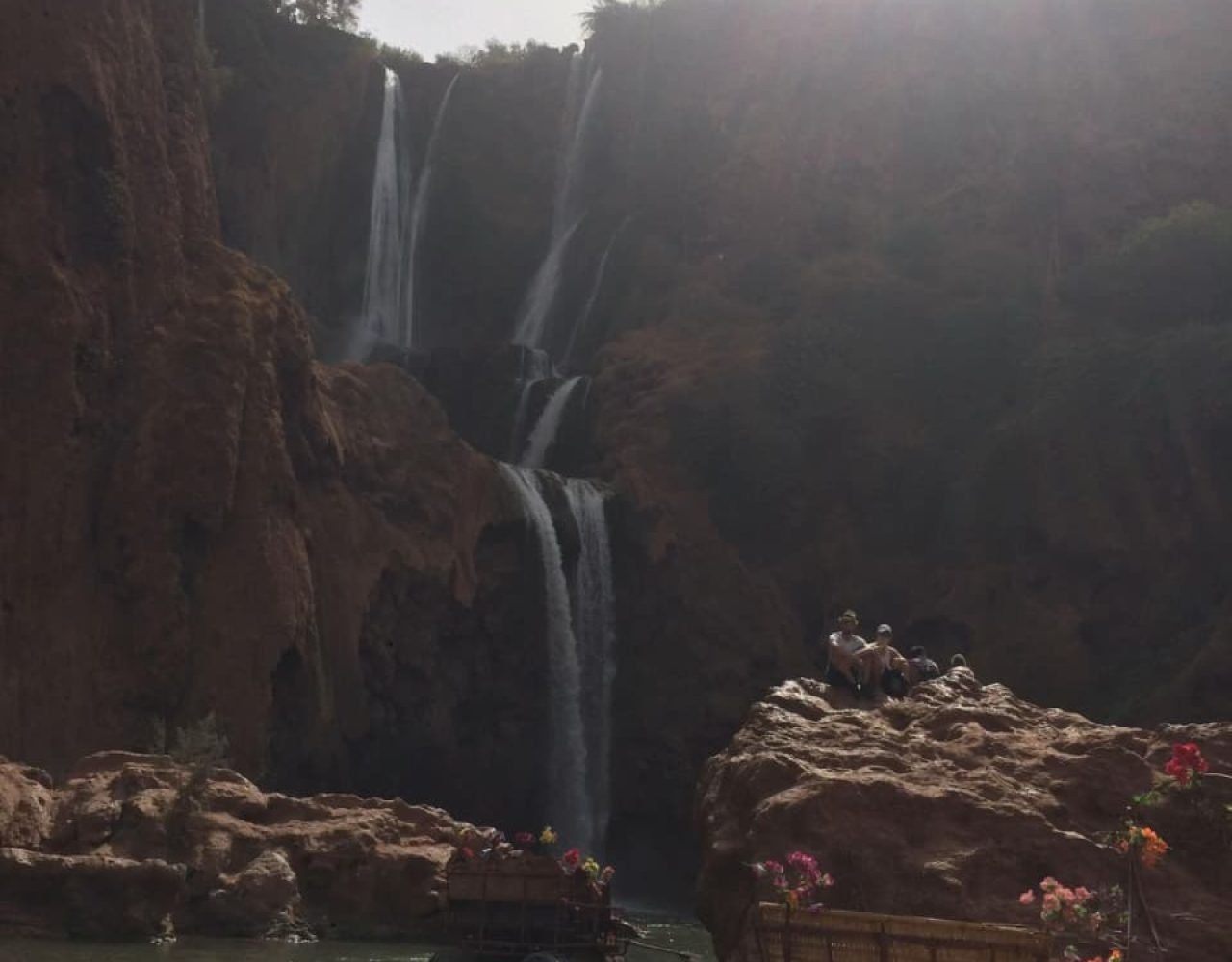 Powerful narrow waterfall cascading through green foliage at Ouzoud