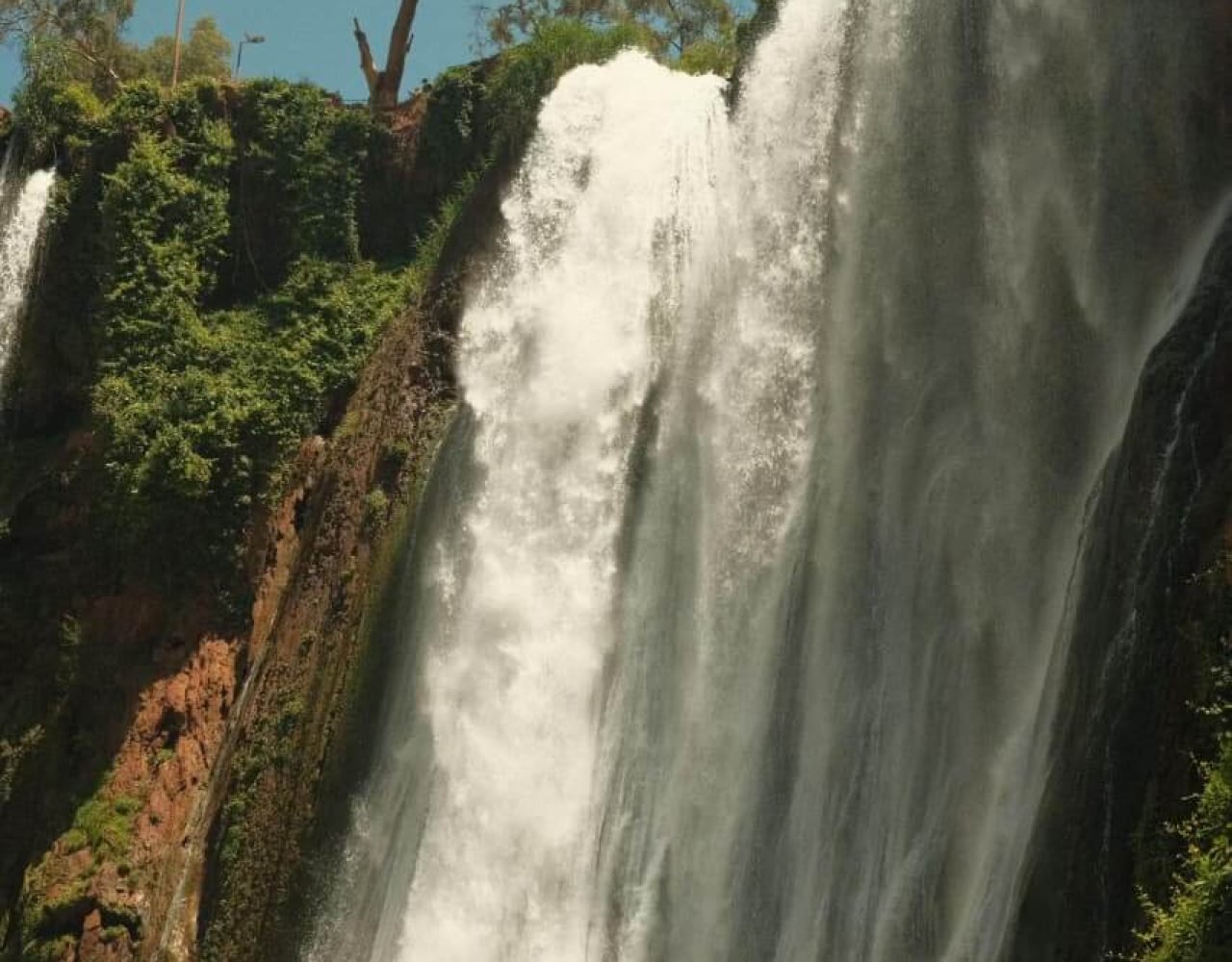 Tall narrow cascade of Ouzoud Falls flowing down a rocky cliff