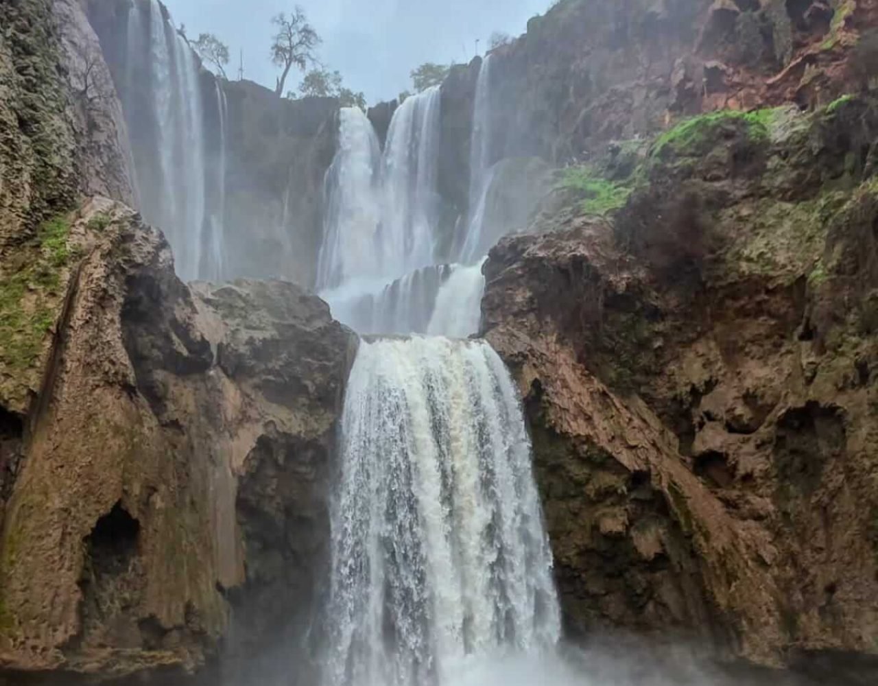 Wide waterfall view of Ouzoud Falls under a hazy sky