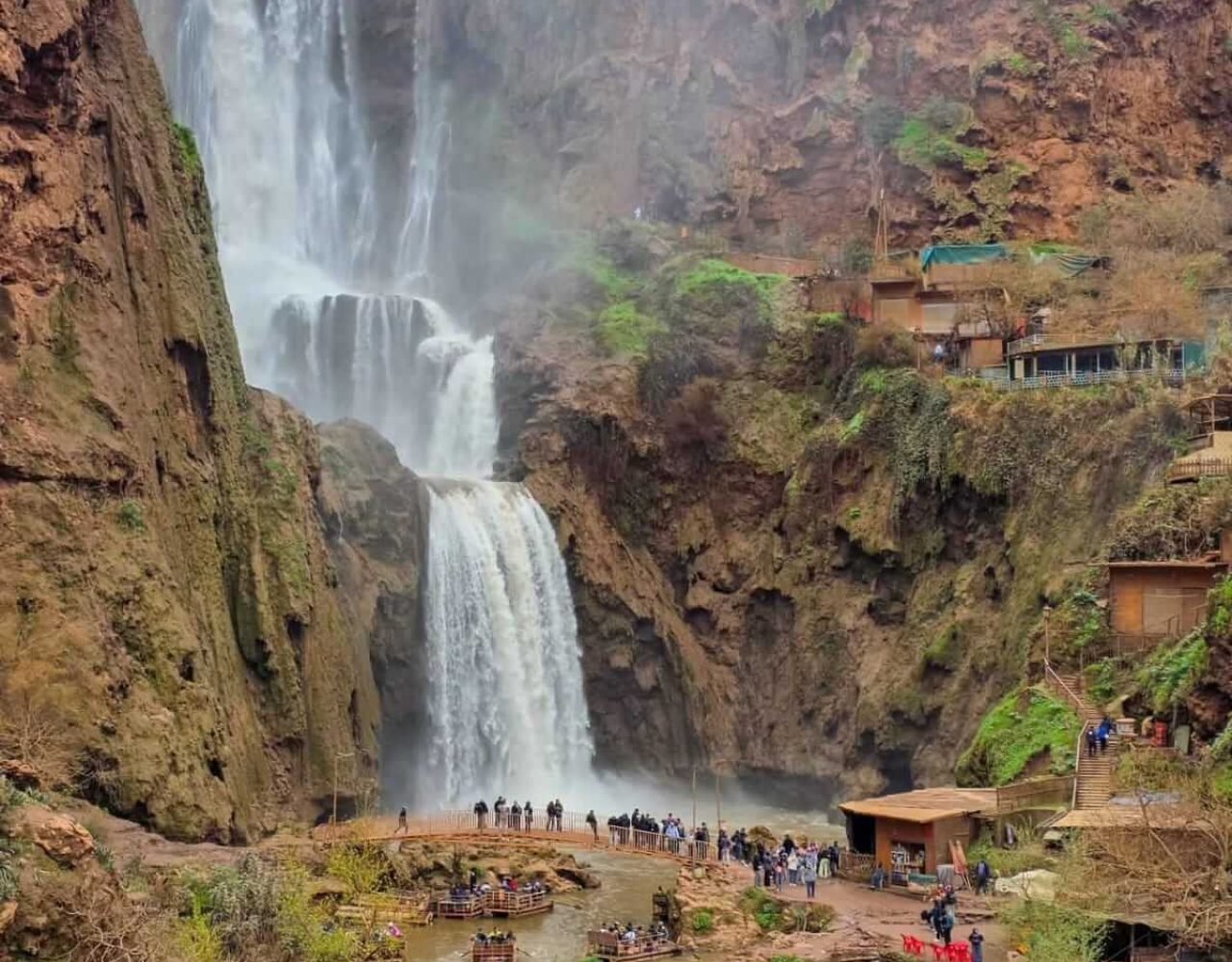 Wide view of Ouzoud Falls from pool level with brownish river water