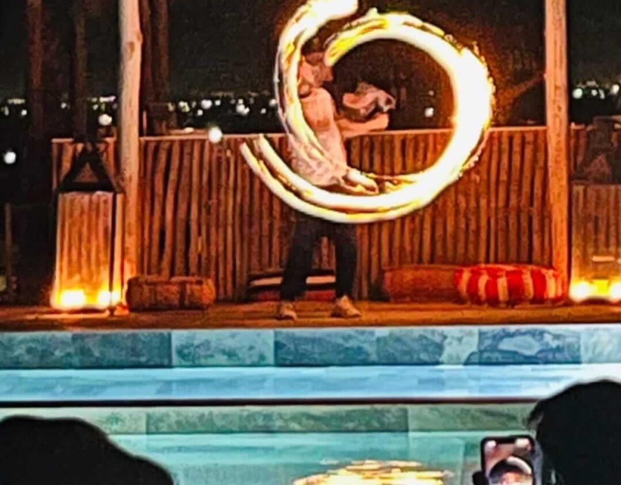 Traditional fire show performance by the pool at an Agafay Desert camp at night