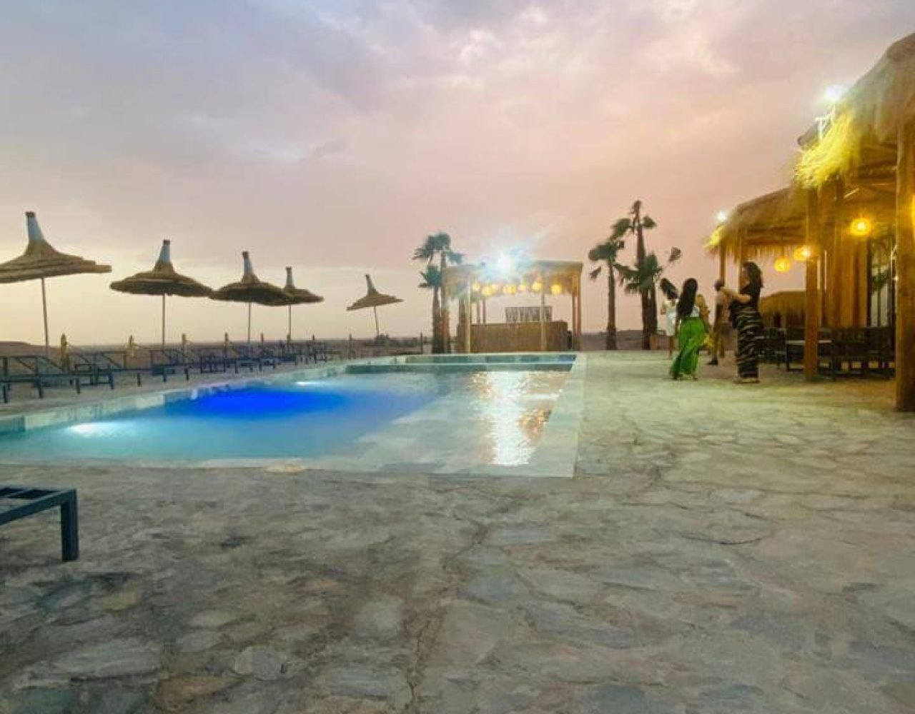 Agafay Desert camp with illuminated pools at dusk near Marrakech