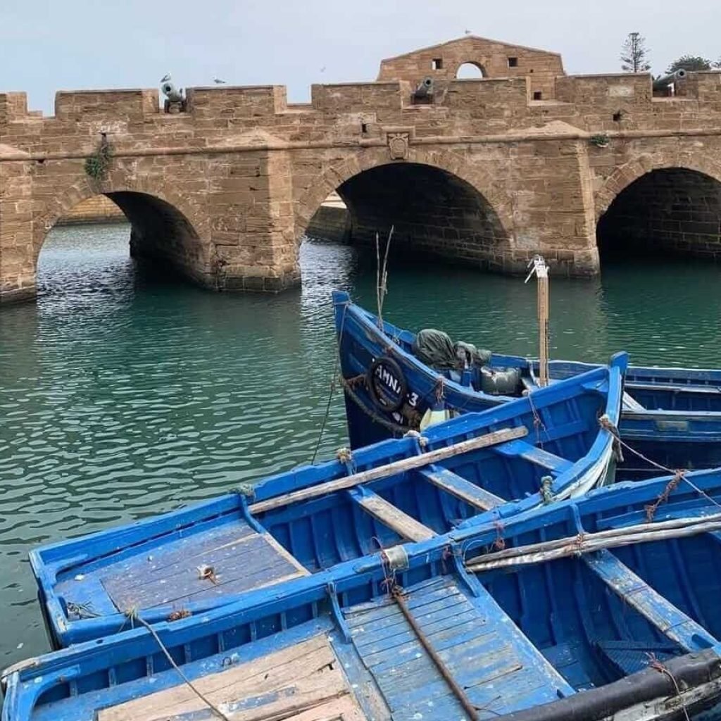 Historic bridge and blue fishing boats in Essaouira harbor