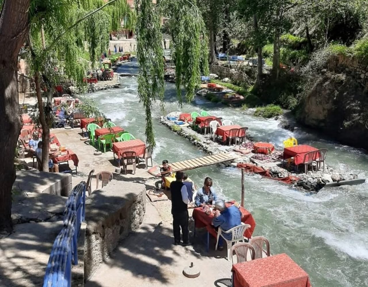 Aerial view of red lounges over Ourika river with visitors walking